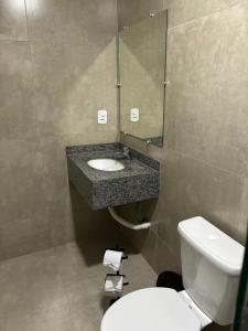 a bathroom with a toilet and a sink and a mirror at Hospedagem Clã dos Couto - Pousada in Saquarema