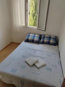 a bed in a room with two pillows and a window at Apartmani Ferri 2 in Vrbanj