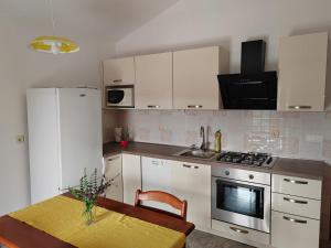 a kitchen with white appliances and a table with a yellow table cloth at Apartmani Ferri 2 in Vrbanj