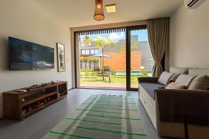 a living room with a couch and a tv at Flat with Direct Pool Access in Japaratinga