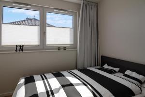 1 Schlafzimmer mit einem schwarzen und weißen Bett und 2 Fenstern in der Unterkunft Ferienwohnnung Penthouse Schönberg - Kalifornien in Schönberg