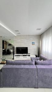 a living room with a large couch and a tv at Apto Guaruja in Guarujá