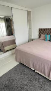 a bedroom with a large bed and a mirror at Apto Guaruja in Guarujá
