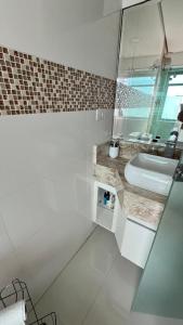 a white bathroom with a sink and a mirror at Apto Guaruja in Guarujá +15 photos