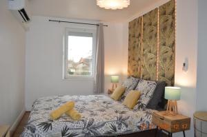 a bedroom with a bed with yellow pillows and a window at Maison Althéa - Calme, Spa & Extérieur plein sud in Lempty