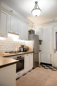 una cucina con mobili bianchi e un frigorifero in acciaio inossidabile di Art Deco Apartment a Constanţa