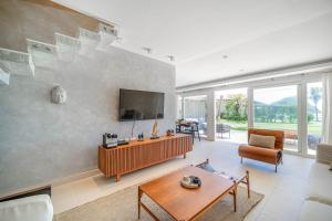 ブジオスにあるBz77 Pé na areia! Casa com jacuzzi e 4 suítesの壁に薄型テレビが取り付けられたリビングルーム