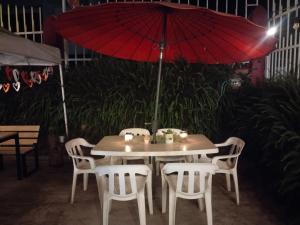 a table with white chairs and a red umbrella at Casa Alto de la Virgen DeMaiz in Choachí