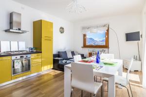 cocina y comedor con mesa blanca y armarios amarillos en Apartment Magnolia A - Musso, en Musso