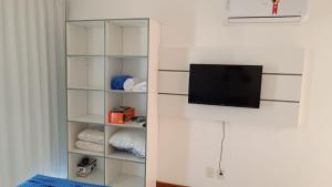 a white book shelf with a tv on a wall at Flat Club meridional B3 1ps in Tamandaré