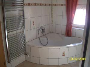 a bath tub with a shower in a tiled bathroom at Ferienwohnung Ruth und Ewald Matt in Herrischried +4 photos