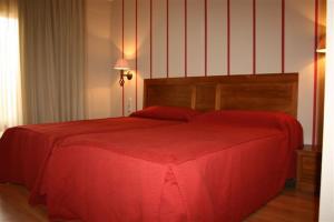 a bedroom with a red bed with a red blanket at Hotel Cariñena in Cariñena
