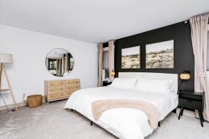 ein Schlafzimmer mit einem weißen Bett und einer schwarzen Wand in der Unterkunft Chic Central 4BDRM Home-King Bed-AirHockey-Mins DT in Edmonton