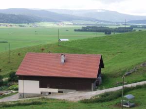 a barn with a red roof on a green field at Chambres d'hôtes Petit Martel in Les Ponts-de-Martel +15 photos