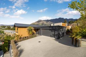 a house with a garage and mountains in the background at Remarkable River Retreat in Queenstown Airport