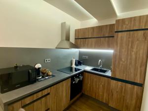 a kitchen with wooden cabinets and a sink and a microwave at Pegazus Apartman in Keszthely