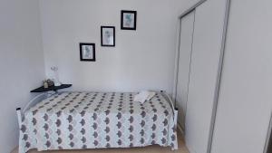 a white bedroom with a bed and three pictures on the wall at Jazmín del cielo Monoambiente independiente interno in Paraná