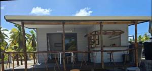 a pavilion with tables and stools on a patio at Tematavainui lodge in Tikehau Airport