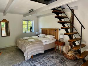 a bedroom with a bed and a spiral staircase at Wisteria Österlen in Simrishamn