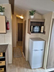a kitchen with a white refrigerator and a microwave at A&J Caravan Hire Golden Gate Towyn in Kinmel Bay