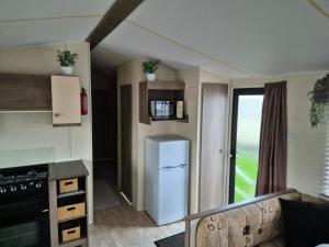 a small kitchen with a refrigerator and a stove at A&J Caravan Hire Golden Gate Towyn in Kinmel Bay