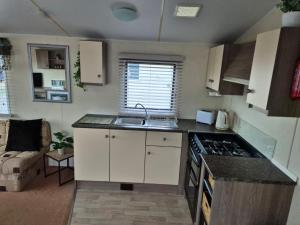 a small kitchen with a sink and a stove at A&J Caravan Hire Golden Gate Towyn in Kinmel Bay