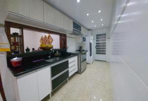 eine weiße Küche mit Spüle und Kühlschrank in der Unterkunft Casa Ponta da Fruta - Piscina, Praia e Conforto in Vila Velha