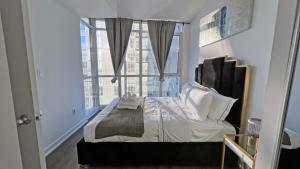 a bedroom with a bed and a large window at Downtown Oasis Condo with Balcony & Free Parking in Toronto