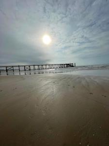 ein Pier am Strand mit der Sonne am Himmel in der Unterkunft Les Voiles Blanches, T3 neuf de 53 m2 in Saint-Jean-de-Monts + 8 Fotos