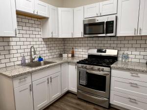 a kitchen with white cabinets and a stove and a microwave at Cozy Tower Hideaway in Fresno