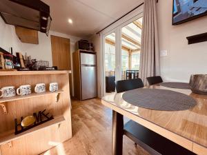 a kitchen and dining room with a table and a room at Les Charmettes Mobilhome 2 ch Climatisé - Terrasse Totalement Abritée - Locsweethome in Les Mathes