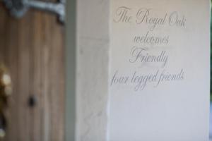 un cartel en una puerta que lee el roble real da la bienvenida a cuatro amigos anteriormente arrendados en The Royal Oak en Ansty