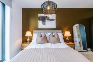 a bedroom with a large bed with pillows and a chandelier at Leeds City Centre - Luxury 2 Bed - Free Parking in Leeds