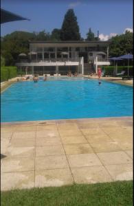 a large blue swimming pool with people in it at Muy buen apartamento con parrilla y piscina, en country in Pilar