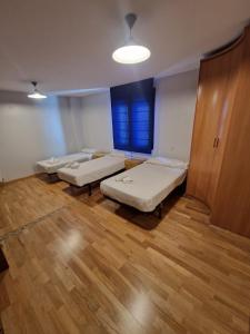 three beds in a room with a wooden floor at Gran piso en el centro de Huesca in Huesca