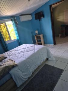 a bedroom with a bed with a blue wall at Paradis Spiritain in Saint Esprit +37 photos