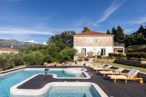 a villa with a swimming pool in front of a house at Holiday Home Korda in Gruda