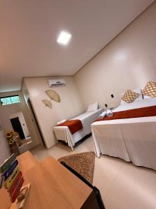 a hotel room with two beds and a table at JM Pousada Barreirinhas MA in Barreirinhas