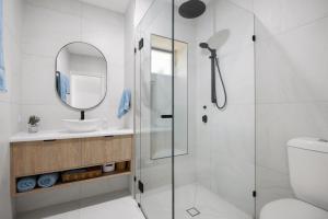 a bathroom with a shower and a sink and a mirror at 1-5 Petrel Street Peregian Beach QLD 4573 in Peregian Beach