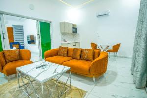 Hôtel détente assinie في أسيني: غرفة معيشة مع كنبتين برتقال وطاولة