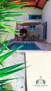 Hôtel détente assinie في أسيني: حمام سباحة مع أرجوحة ومظلة