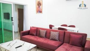 Hôtel détente assinie في أسيني: غرفة معيشة مع أريكة حمراء وطاولة