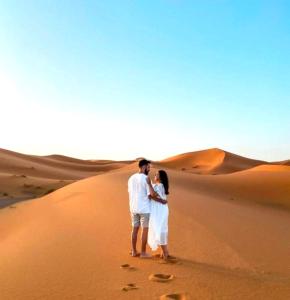a man and a woman standing in the desert at Private Luxury Camp in Merzouga