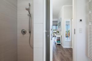 La salle de bains blanche est pourvue d'une douche et d'un couloir. dans l'établissement Ostsee - Appartement Nr 80 "MeerSinn" im Strand Resort, à Heiligenhafen