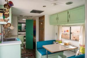 a kitchen with green cabinets and a table with a blue chair at Beach cozy fresh vibes RV in Ensenada