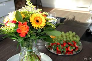 eine Vase aus Blumen auf einem Tisch mit Obstteller in der Unterkunft Ostsee - Reetdachhaus Nr 9 "Emma" im Strand Resort in Heiligenhafen