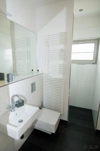 ein weißes Badezimmer mit Waschbecken und Dusche in der Unterkunft Ostsee - Reetdachhaus Nr 9 "Emma" im Strand Resort in Heiligenhafen + 16 Fotos