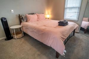 a bedroom with a bed with a pink comforter at Historic Route-66 Bungalow in Springfield