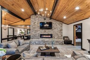a living room with a stone fireplace and a couch at Honeybear Hideaways - Luxurious Modern 7BR Cabin with Indoor Pool, Game Room, Hot Tub & Fireplace in Sevierville