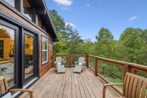 a wooden deck with chairs and a house at Honeybear Hideaways - Luxurious Modern 7BR Cabin with Indoor Pool, Game Room, Hot Tub & Fireplace in Sevierville